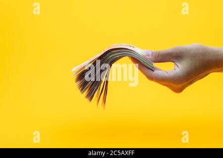 Hand hält einen Wad Geld, gelber Hintergrund Stockfoto