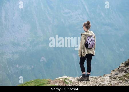 Eine junge Dame blickt über den Rand von Helvellyn in Richtung Striving Edge im Lake District Stockfoto