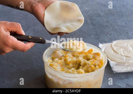 Eine Hand, die zum Füllen eines Teigs Empanadas mit Maiscreme. Argentinisches Essen. Stockfoto