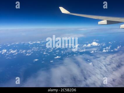 Wolken am blauen Himmel durch das Flugzeugfenster gesehen Stockfoto