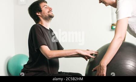 Physiotherapeut mit behinderten Menschen auf einem Therapietisch mit einem Ball trainieren. Stockfoto