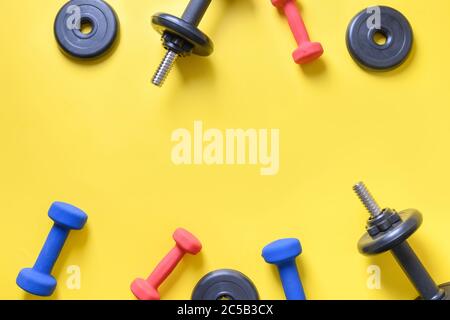 Set von Kurzhanteln auf gelbem Hintergrund. Draufsicht, Kopierbereich. Stockfoto