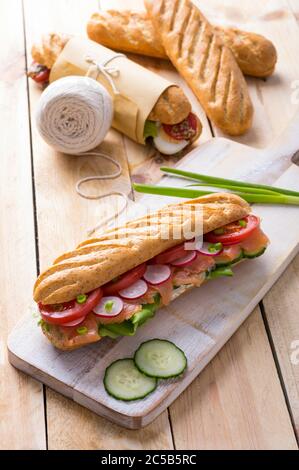 Frische U-Boot-Sandwiches mit verschiedenen Füllungen auf Holzhintergrund Stockfoto