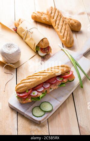 Frische U-Boot-Sandwiches mit verschiedenen Füllungen auf Holzhintergrund Stockfoto