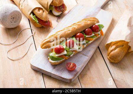 Frische U-Boot-Sandwiches mit verschiedenen Füllungen auf Holzhintergrund Stockfoto