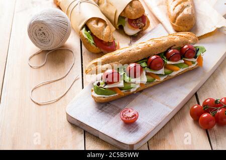 Frische U-Boot-Sandwiches mit verschiedenen Füllungen auf Holzhintergrund Stockfoto