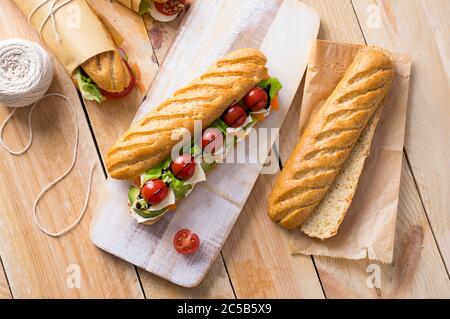 Frische U-Boot-Sandwiches mit verschiedenen Füllungen auf Holzhintergrund Stockfoto