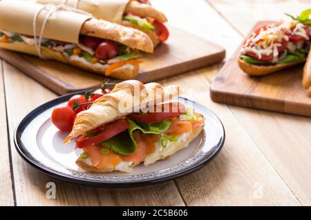 Frische U-Boot-Sandwiches mit verschiedenen Füllungen auf Holzhintergrund Stockfoto