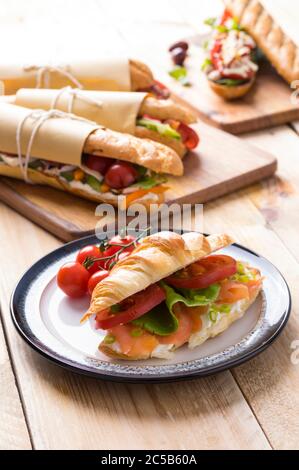 Frische U-Boot-Sandwiches mit verschiedenen Füllungen auf Holzhintergrund Stockfoto