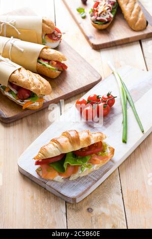 Frische U-Boot-Sandwiches mit verschiedenen Füllungen auf Holzhintergrund Stockfoto