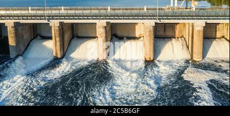 Luftpanorama des Wasserrausches durch die Tore beim Damm des Wasserkraftwerks. Stockfoto