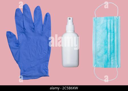 Schutzhandschuh, Alkoholdesinfektionsmittel und Maske auf rosa Oberfläche Stockfoto