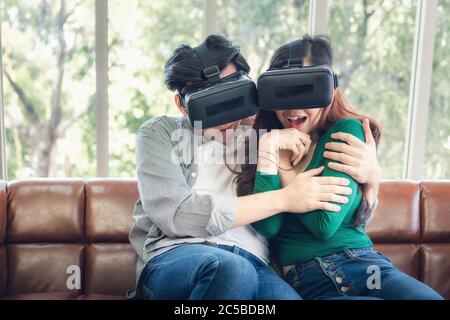 Junges Paar Spaß Spannende Beim Ansehen Video Über Virtual Reality Zusammen. Pärchen lieben es, mit elektronischen VR-Videospielen auf der Couch zu spielen. Stockfoto