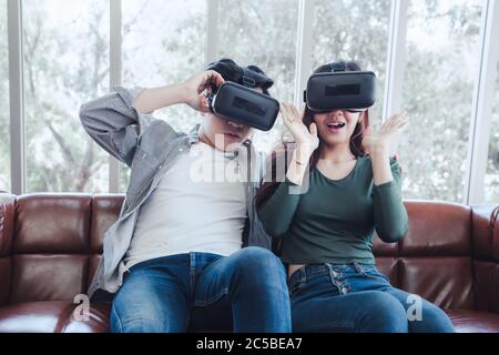 Junges Paar Spaß Spannende Beim Ansehen Video Über Virtual Reality Zusammen. Pärchen lieben es, mit elektronischen VR-Videospielen auf der Couch zu spielen. Stockfoto