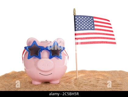 Traditionelles rosa Sparschwein trägt Sterngläser im Sand mit American Flag winken, isoliert auf weiß. Stockfoto