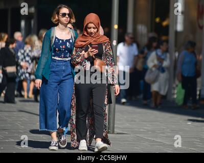 Italienische junge Mädchen, eine von ihnen muslimen, hören Musik zusammen, während Sie in der Via Sparano da Bari spazieren. Bari, Italien Stockfoto