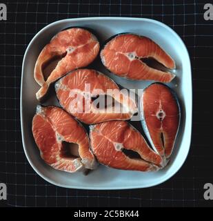 Lachssteaks liegen auf einer weißen quadratischen Keramikplatte. Roter Fisch Stockfoto