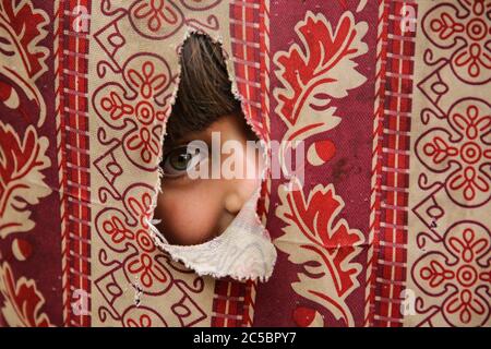 Peking, China. Juni 2020. Ein palästinensisches Kind schaut durch ein Loch auf einer Decke im Shati Flüchtlingslager in Gaza City, 7. Juni 2020. Kredit: Rizek Abdeljawad/Xinhua/Alamy Live Nachrichten Stockfoto