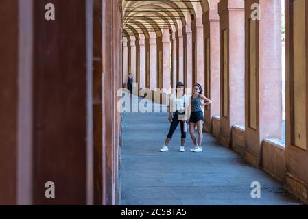 Mutter mit Hut und Tochter mit Hand an der Hüfte im Portico in Bolgona Italien Stockfoto