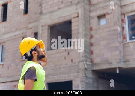 Junger Ingenieur im Arbeiter Helm auf unscharfen Hintergrund Stockfoto
