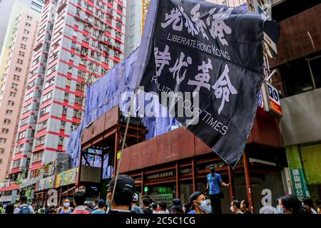 Ein Protestler hält die Flagge "Befreie Hongkong, Revolution unserer Zeit" während der Demonstrationen. Das nationale Sicherheitsgesetz ist ein von Peking für Hongkong eingeführtes Gesetz. Er besteht aus 66 Artikeln, die bis nach ihrer Beendung geheim waren und kriminalisiert alle Sezessionshandlungen, Subversion, Terrorismus und Absprachen mit ausländischen oder externen Kräften mit einer maximalen Freiheitsstrafe. Das Gesetz trat offiziell um 30 Uhr am 2020. Juni in Kraft - am Abend vor dem 23. Jahrestag der Übergabe Hongkongs von Großbritannien an China. Am 1. Juli kamen Tausende Stockfoto