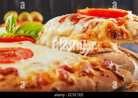 Der köstliche Geschmack von Pizza und Käsescheiben mit Mozzarella und Tomaten. Dreieckspizza mit Stretching-Käse und Gewürzen. Nahaufnahme Stockfoto