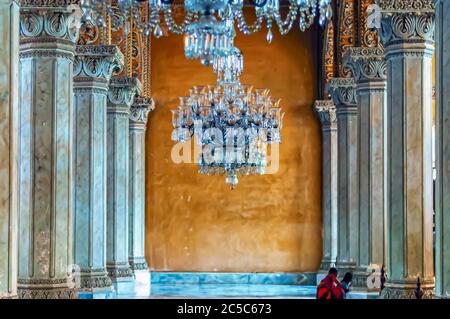 Marmorsäulen mit Schnitzereien umgeben die Kronleuchter, die an der Decke von Nizams Wohnstätte im Chowmahalla Palace, Hyderabad, Telangana, Indien, hängen. Stockfoto