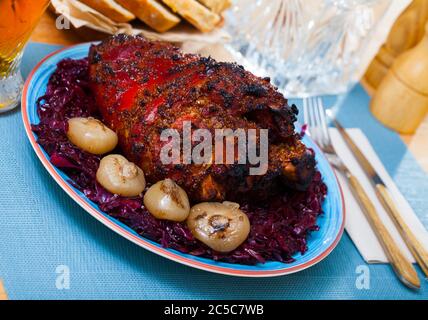 Lecker gebratene Schweinshaxe mit Beilage von geschmorten Rotkohl und Zwiebel Stockfoto