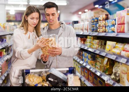 Portrait des Mannes mit Freundin einkaufen Cracker und Snacks in der Lebensmittelabteilung des Supermarkts Stockfoto