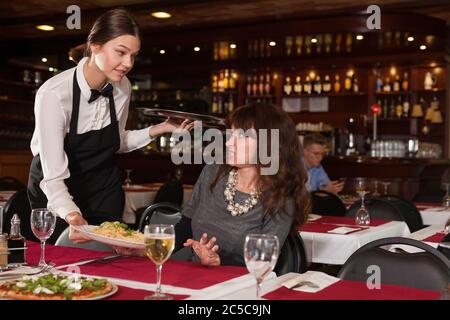 Weibliche kunden Unzufriedenheit mit dem bestellten Teller durch junge Kellnerin im Restaurant serviert. Stockfoto