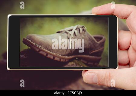 Schuhe auf dem Smartphone-Bildschirm. Neue stilvolle braune Herrenschuhe. Stockfoto