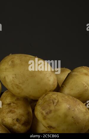 Rohe frische Bio-Kartoffeln auf Holztisch vor dunklem Hintergrund. Stockfoto