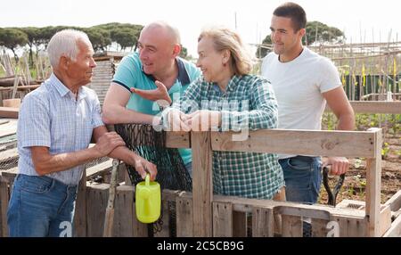 Familie von vier Gärtner zusammen gesprochen in der Nähe von hölzernen Zaun im Garten outdoor Stockfoto