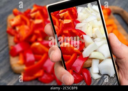 Sliced ​​vegetables auf dem Smartphone-Bildschirm. Kochen in der Küche. Stockfoto