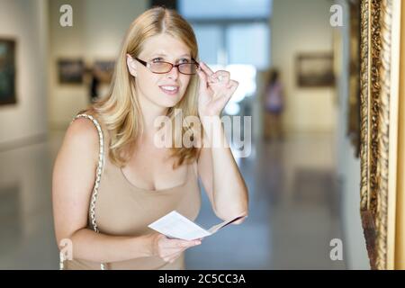 Frau mit schlechtem Sehvermögen Besuch Museum und das Betrachten der Bilder durch Gläser Stockfoto