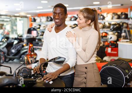 Glücklich positive lächelndes junges Paar zufrieden mit der Wahl in modernen Motorrad-Salon Stockfoto