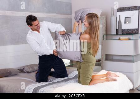 Freundliche liebevolle Paar Kissenschlacht im Schlafzimmer zu Hause Stockfoto