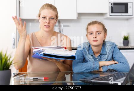 Umgekippt Mutter Kontrolle Hausaufgaben Ihrer ängstlichen Tochter im Teenageralter in der Küche Stockfoto