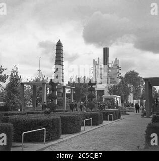 Ein Blick auf die Expo 1937 in Paris, Frankreich – hier schlendern die Menschen in den "Séctions des Jardins", Gärten entlang der seine. Im Hintergrund ist ein Pavillon für das französische Energieunternehmen Gaz. Stockfoto