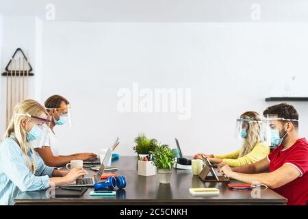 Junge Menschen arbeiten in Co-Working kreativen Raum tragen chirurgische Maske Schutz zur Verhinderung der Corona-Virus-Ausbreitung Stockfoto