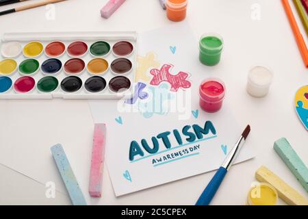 Karte mit Autismus Awareness Day Schriftzug und Bemalung von Puzzle auf weiß mit Farben und Kreiden Stockfoto