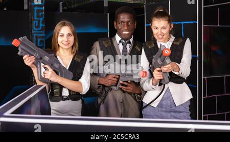 Afrikanische Mann und zwei jungen kaukasischen Frauen holding Laser Gewehren und auf der Laser tag Zimmer posing Stockfoto