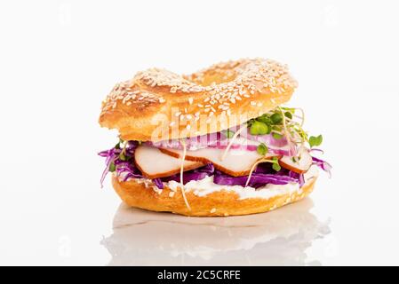 Frischer, köstlicher Bagel mit Fleisch, roten Zwiebeln, Frischkäse und Sprossen auf weißem Hintergrund Stockfoto