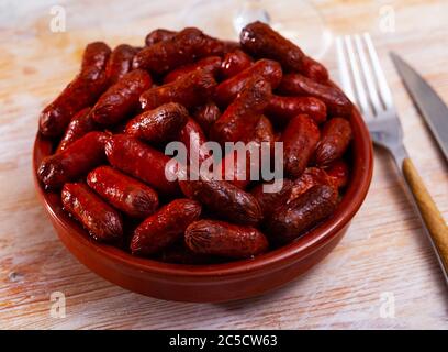 Mild gewürzte gegrillte Mini-Würstchen Chistorra. Lieblingstapa aus der baskischen Küche Stockfoto