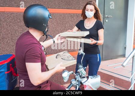 Lieferung von Lebensmitteln per Kurier in einer medizinischen Maske während der Quarantäne. Stockfoto