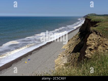 Blick nach Osten entlang der erodierenden Lehmklippen von Norfolk in Richtung Sheringham, wo sich die schnell erodierenden Felsformationen und der Kiesstrand zeigen. Stockfoto