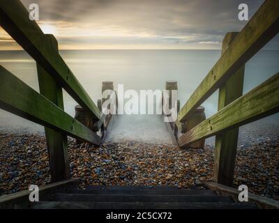 Eine Holztreppe zum Strand bei Jurys Gap in der Nähe von Camber Sands, der bei Flut bedeckt ist. Stockfoto