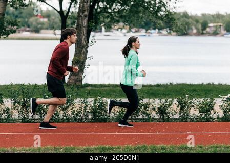 Seitenansicht des Paares auf Laufstrecke im Park Stockfoto