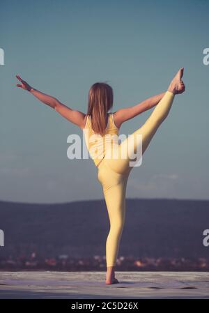 Schöne blonde Mädchen Tänzerin tun Stretching auf dem Dach gegen den Himmel und die Berge Stockfoto