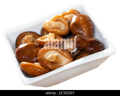 Köstliche hausgemachte eingelegte Shiitake Pilze garniert mit Zwiebeln auf weißem Teller. Isoliert auf weißem Hintergrund Stockfoto